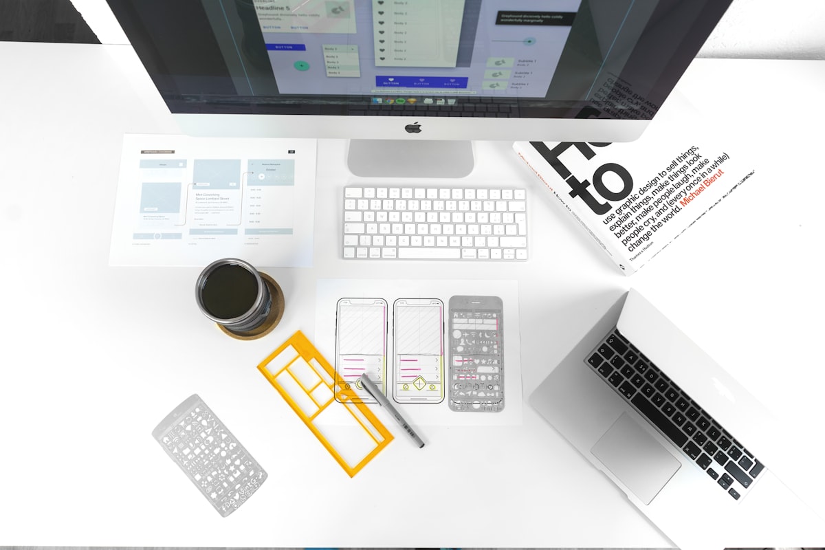 App wireframes and a phone laid out on a desk