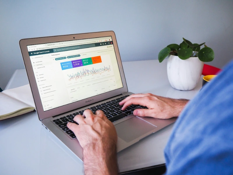 A marketer reviewing website performance data and google ads analytics on a laptop.