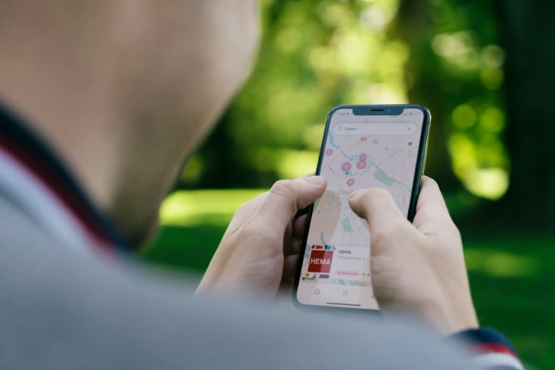 Person holding a smartphone displaying a map application with multiple location pins.